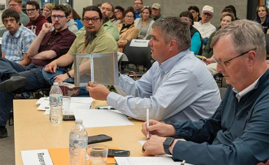 Badger Venture judge John Stanaland of Business Oregon asks team Fire Stoppers about their  ember-arresting screen at the annual event April 23 on the Klamath Community College campus. 